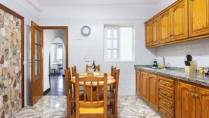 A kitchen with a dining table, wooden cabinets, and a stone wall. - Apartamento Campo Rosa Tacoronte (Tacoronte)