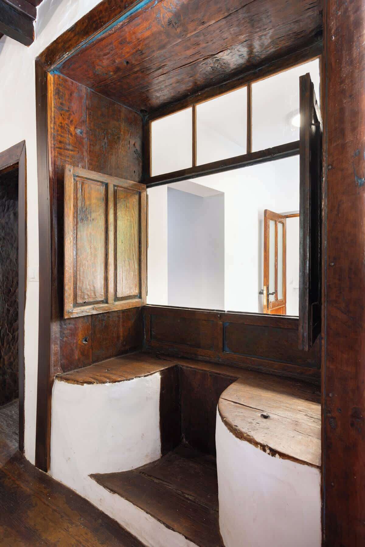 A rustic bathroom with wooden walls, a large mirror, and a wooden bench.