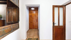 Um corredor com porta de madeira, tapete de entrada e escada que leva a outro cômodo.