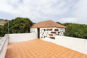 Una terrassa al terrat amb paviment de rajola i un edifici petit amb teulada de rajola.