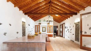 Um quarto espaçoso com teto de madeira alto, uma mesa comprida de madeira e bancos.