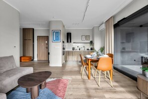 A modern living room with a sofa, coffee table, and dining area with chairs. - Górczewska Apt - Balcony, Parking, A/C - by Rentujemy (Warszawa)