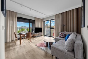 A modern living room with a sofa, TV, dining table, and chairs. - Górczewska Apt - Balcony, Parking, A/C - by Rentujemy (Warszawa)