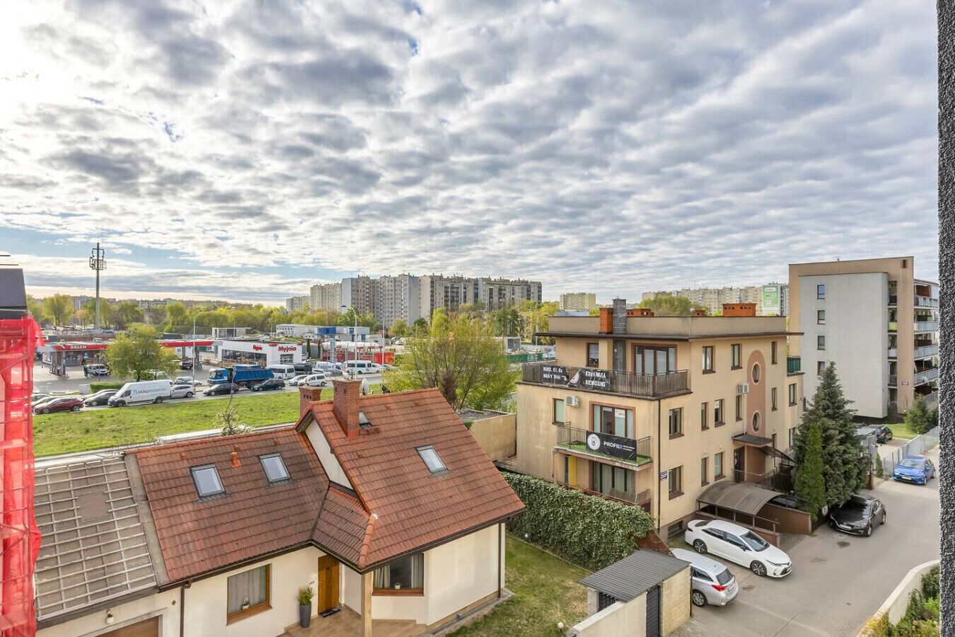 A residential area with a mix of apartment buildings, a parking lot, and a gas station.