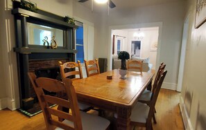 Comedor con mesa de madera, seis sillas, chimenea y candelabro.