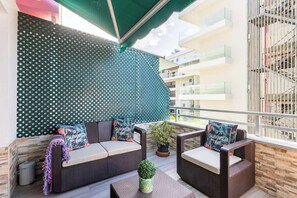 A balcony with a sofa, chairs, a small table, and a potted plant. - Apartamento Terraza Martianez (Puerto de la Cruz)