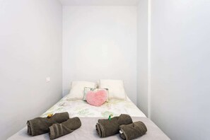A single bed with a floral bedspread, a heart-shaped pillow, and rolled towels on the bed. - Apartamento Terraza Martianez (Puerto de la Cruz)