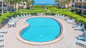 Ein Pool mit Liegestühlen und Blick aufs Meer.