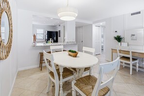 Uma cozinha moderna com armários brancos, uma mesa de jantar redonda e cadeiras de vime.