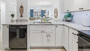 Una cucina moderna con mobili bianchi, lavastoviglie integrata e una grande isola con lavello.