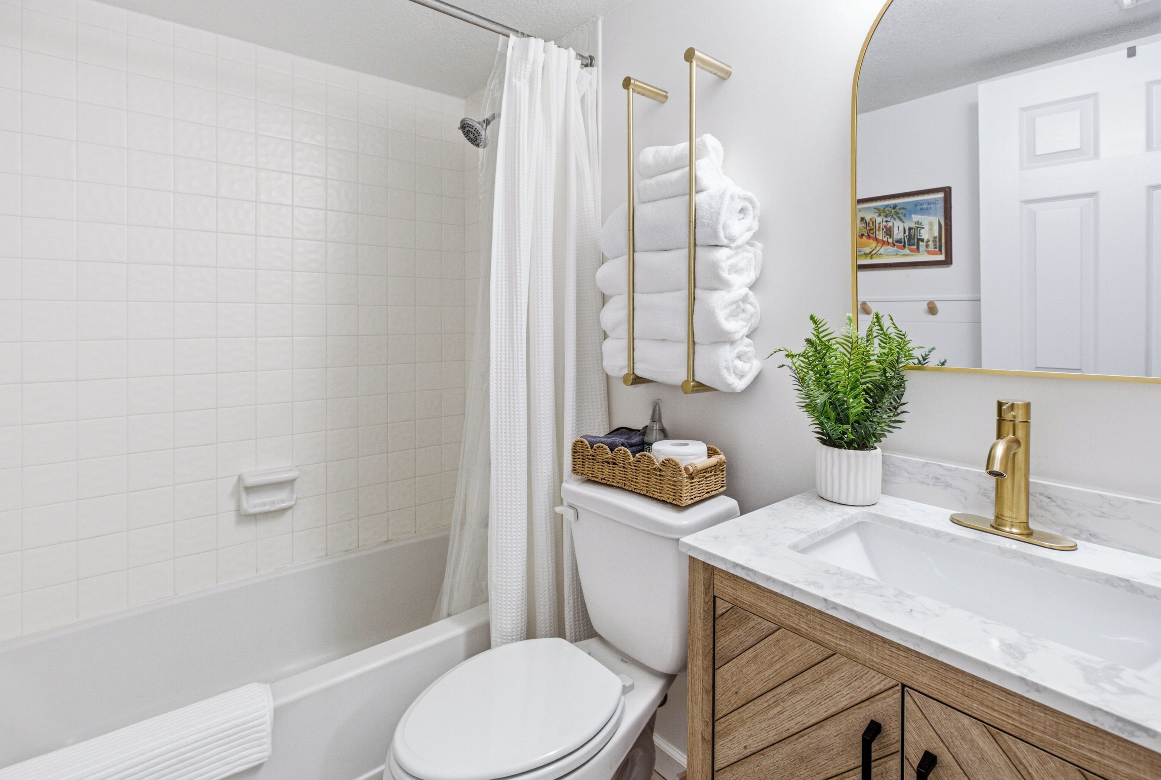 Et badeværelse med brusebad, toilet, håndvask og spejl.