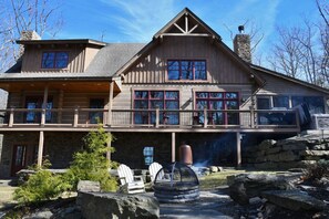 Eine große Blockhütte mit Steinunterbau, mehreren Fenstern und einer Terrasse.