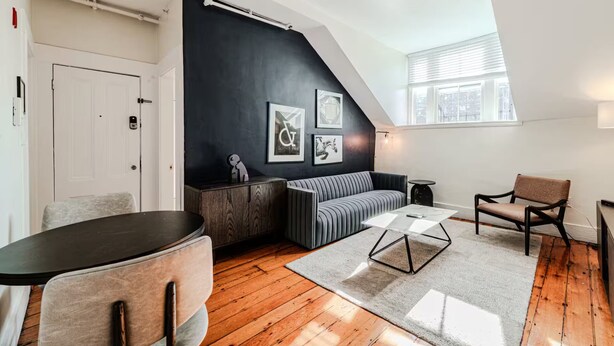 Ein modernes Wohnzimmer mit schwarzer Akzentwand, einer Couch, einem Couchtisch und Holzboden.