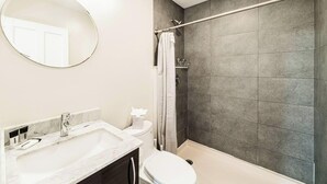 Ein Badezimmer mit Badewanne, Toilette, Waschbecken, Duschvorhang und Spiegel.