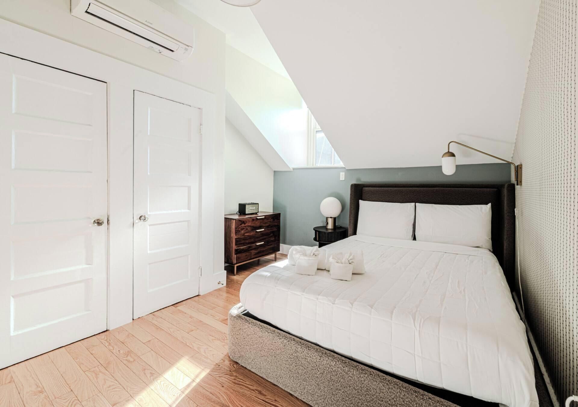 A bedroom with a bed, a dresser, a nightstand, and a ceiling fan.