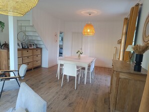 Ein Essbereich mit Tisch, Stühlen, einer Pendelleuchte und einer Treppe.