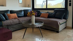Una sala de estar moderna con un sofá seccional, una mesa de centro redonda y un ventanal con vistas al exterior.