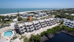 Un hôtel situé sur la côte, composé de plusieurs bâtiments, doté d’une piscine et offrant une vue sur la plage.