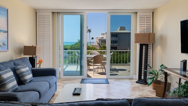 Un salon comprenant un canapé, une table basse, un téléviseur et un balcon avec vue sur l’océan.