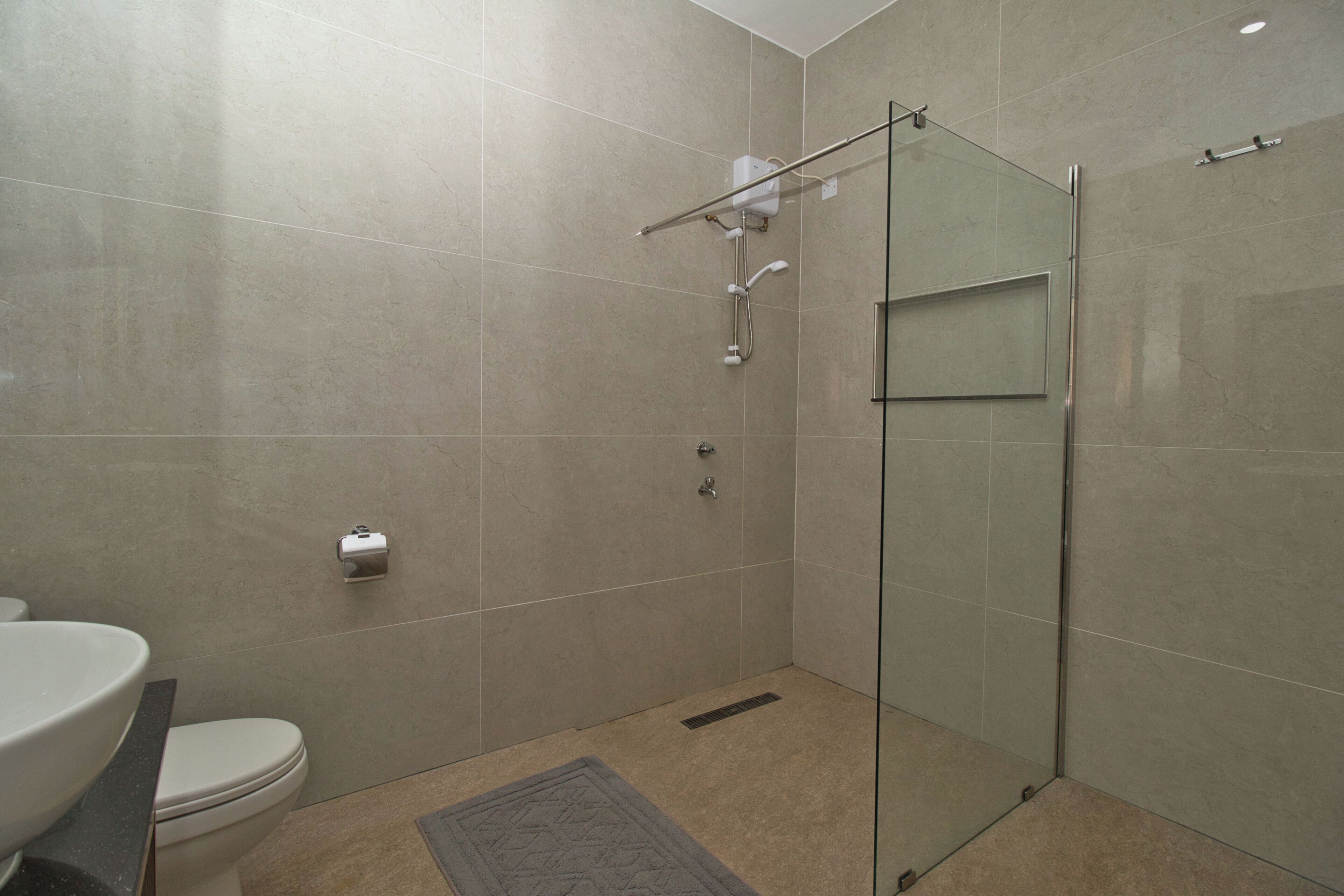 A modern bathroom with a glass shower enclosure, a toilet, and a sink.