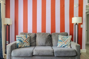 Ein graues Sofa mit gemusterten Kissen vor einer Wand mit vertikalen Streifen.