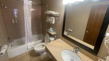 A bathroom with a bathtub, toilet, sink, and a large mirror.