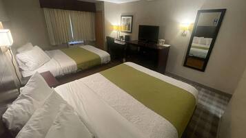 Una habitación de hotel con dos camas, un escritorio, un televisor y un espejo.