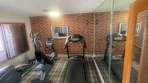 A gym with treadmills, stationary bikes, and a mirror reflecting the equipment.