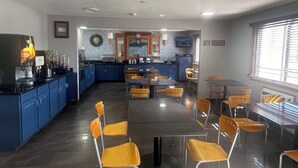 A restaurant with a central dining area, kitchen, and a clock on the wall.