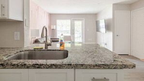 A kitchen with granite countertops, a stainless steel sink, and a dining area with a sofa. - Fruity King 1BR facing NRG |near Med Center | Pool (Houston)
