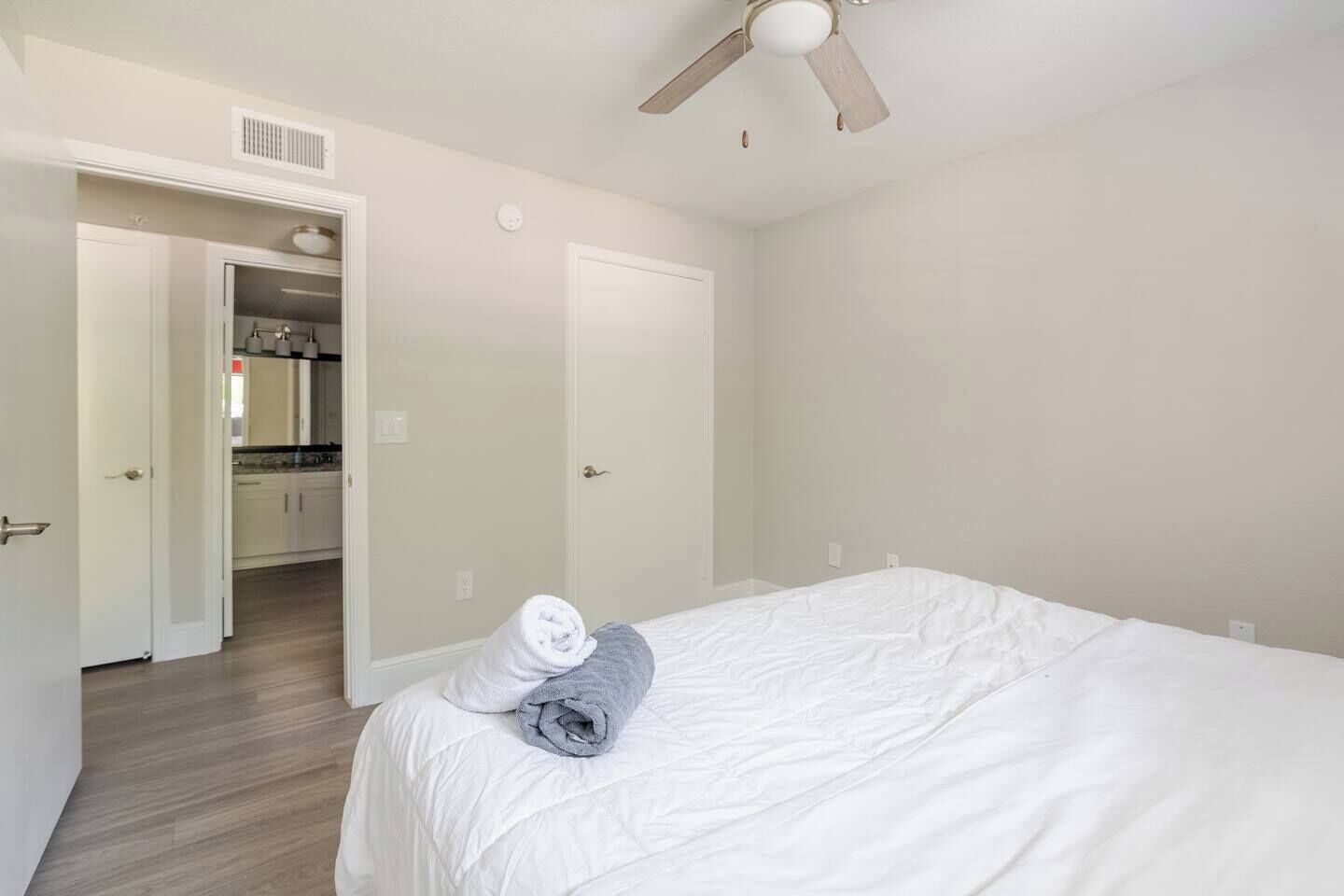 Un dormitorio con una cama, un ventilador de techo y una puerta abierta que da a una cocina.