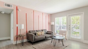 A modern living room with a sofa, a round coffee table, and a lamp. - Fruity King 1BR facing NRG |near Med Center | Pool (Houston)