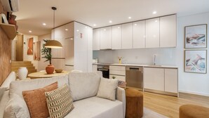 A modern living room with a sofa, ottoman, and a dining area with a table and chairs. - Casa do Livro - E a de Queir s Apartment by Minho (Guimarães)