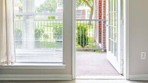 A room with a large window, a door leading outside, and a visible brick wall. - King Queen 2BR /walk to NRG /1mi to MD Anderson (Houston)