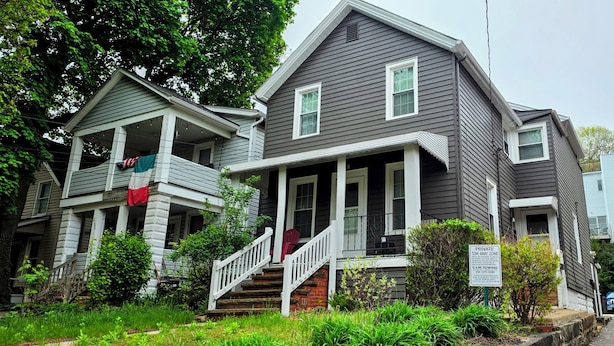 A two-story house with a porch, a staircase, and a 'Private Tow Zone' sign.