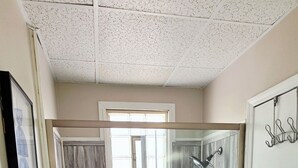 A walk-in shower with a glass door, a towel rack, a door with a towel, and a window.