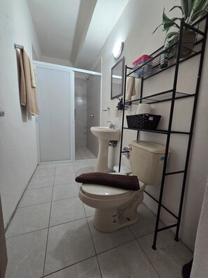 Une salle de bain comprenant des toilettes, un lavabo et une cabine de douche.