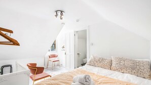 Een slaapkamer met een bed, een stoel, een tafeltje en een radiator.