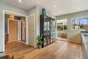 A modern kitchen with a large island, a glass-fronted cabinet, and a view of the outdoors. - Fern Hill - Close to Village and Beach (Saundersfoot)