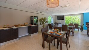 A modern kitchen with a dining area, large windows, and a television. - À proximité de la plage | Accès piscine | Balcon (PLESCOP)