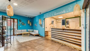 A reception area with a blue wall, a reception desk, a sofa, and hanging wicker lamps.