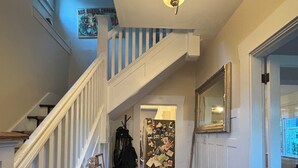 Eine Treppe mit weißer Geländer, ein Chandelier, ein Korridor mit einem gemusterten Teppich und ein mit Fotos beklebter Kühlschrank.