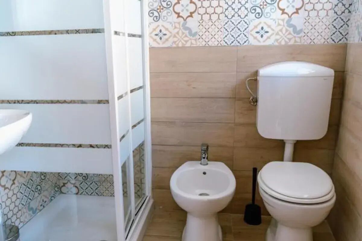 A bathroom with a toilet, bidet, and a sink.