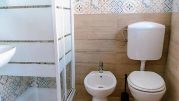 A bathroom with a toilet, bidet, and a sink.