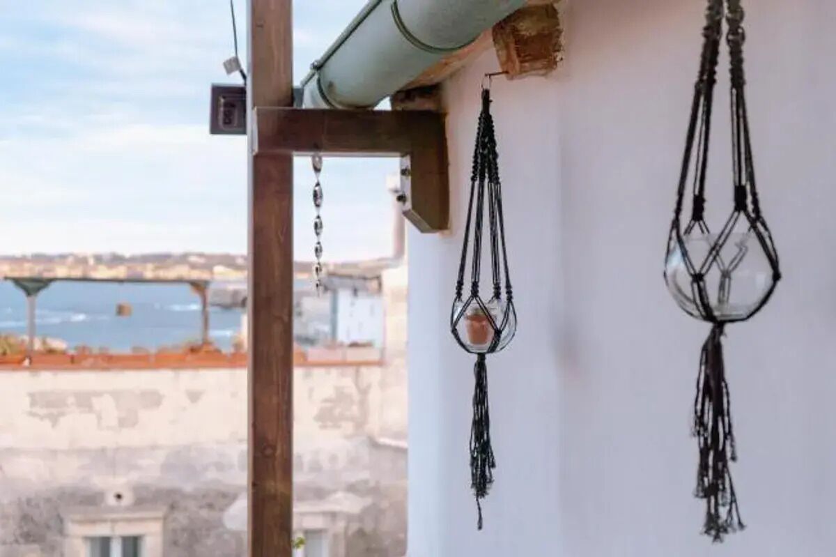 A room with a view of a bridge and a white wall with macrame decorations.