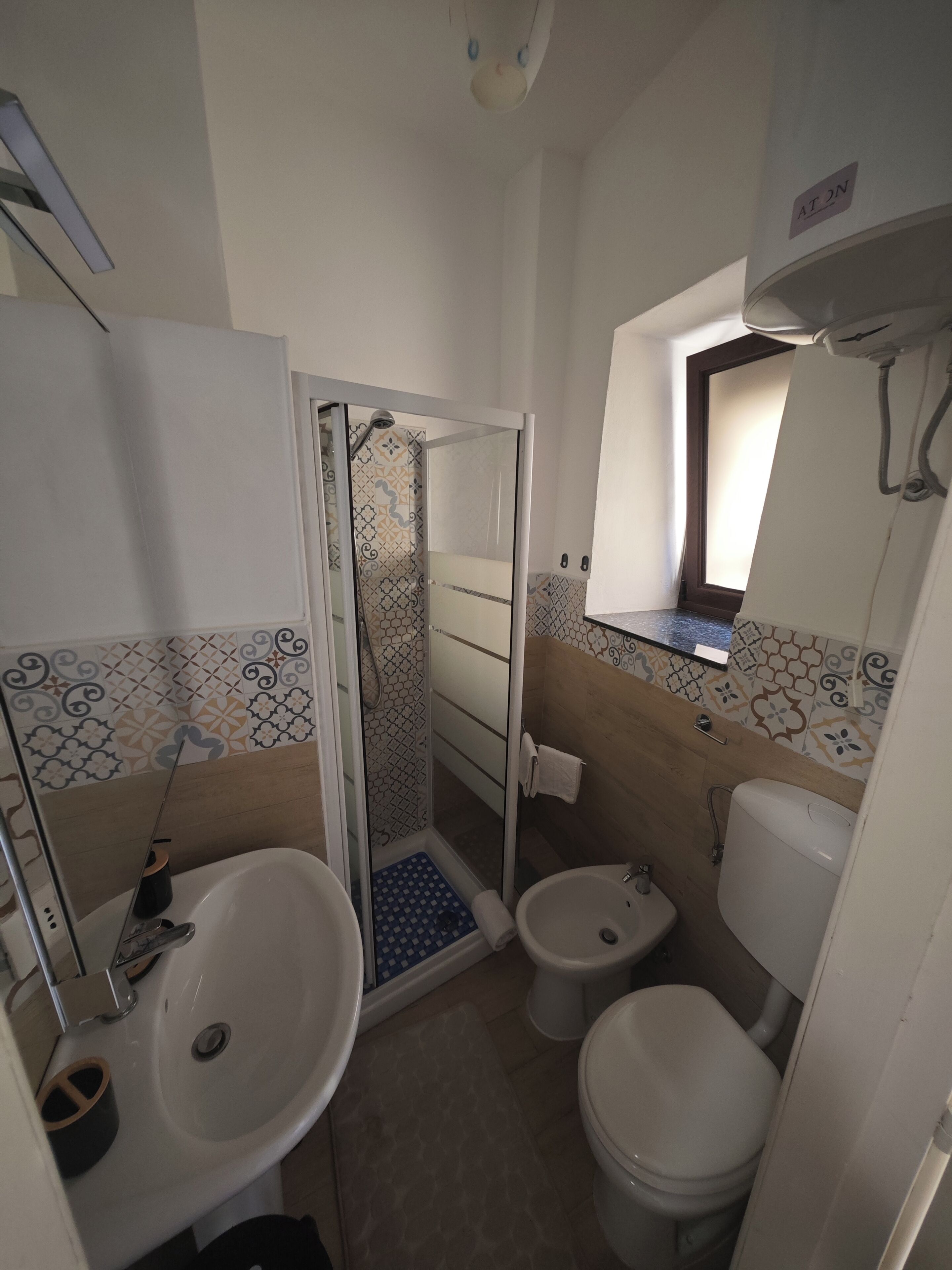 A bathroom with a shower, toilet, bidet, and sink.