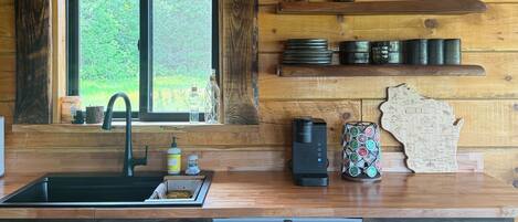 A kitchen with wooden walls, a window, a sink, a coffee maker, and a map decoration.