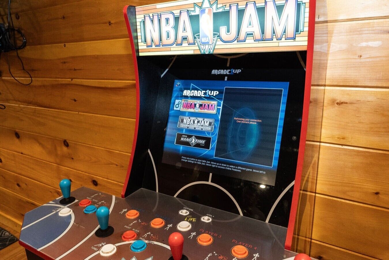 Máquina de jogos de arcade com a marca 'NBA JAM' e botões para 'JOGADOR 1', 'JOGADOR 2', 'JOGADOR 3' e 'JOGADOR 4'.