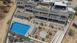 A multi-story building with a rooftop pool, outdoor seating, and a desert landscape. - Modern 4BR Villa with Rooftop & Pickleball (Los Barriles)