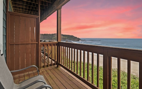 A wooden deck with a view of the ocean and a beach.